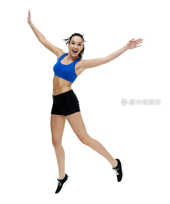 一个人/全长/正面视图/看18-19岁的成年人美丽的黑发/长发/马尾辫高加索女性/年轻女性运动员/运动员跳跃/半空中在白色背景前举起手臂
